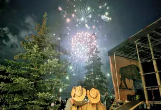Fireworks during Buffalo Days in Grand Lakes, Colorado with two people wearing cowboy hats looking up at the sky. 