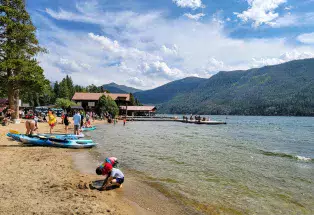 Boats and swimmers on the shores of Grand Lake in Colorado with mountains in the background