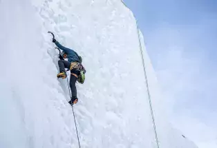 A man uses an ice pick to scale an ice wall in Lake City