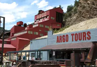 Exterior shot of Argo Gold Mine & Mill in Idaho Springs, Colorado, a bright red building made of several layers built into the mountainside