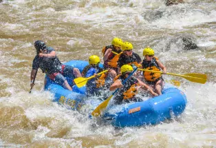 Group of people rides river rapids in a blue raft while Colorado whitewater rafting