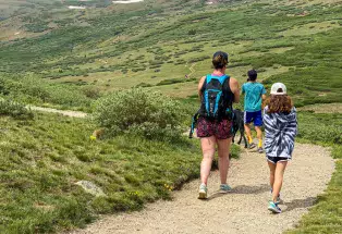 Three people on a hiking trail surrounded by green vegetation