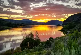 The sherberty colors of sunset reflect in Kremmling's Wolford Mountain Reservoir with mountains in the background