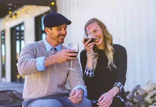 Two people raise their glasses of red wine at Palisade Restoration Vineyards