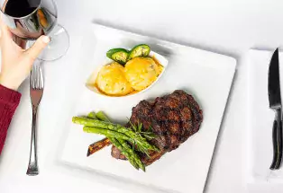 An aerial shot of a fine-dining plate with a steak, asparagus spears and a dish of mango ice cream garnished with jalepeño slices. 