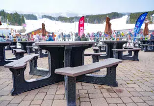 A TerraCycle table made from recycled wrappers stands in the foreground at Breckenridge Ski Resort with the ski runs and diners in the background