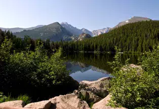 An alpine lake reflects the surrounding peaks on a sunny summer day  in Rocky Mountain National Park