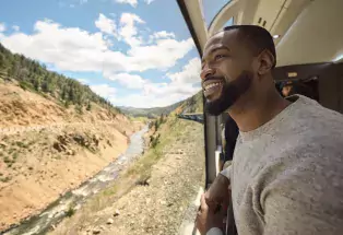 A man gazes out the window of the Rocky Mountaineer train as it runs alongside the Colorado River