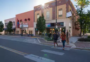A group of happy friends walks across the street amongst the shops and the Skyline Theatre in downtown Cañon City.