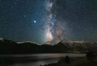 The Milky Way slashes through the night sky and reflects in the surfaces of Twin Lakes in Colorado