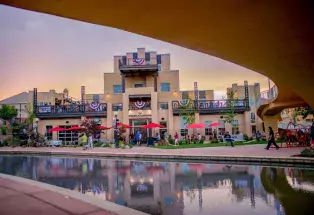 A sunset view of the exterior Pueblo's Brues Alehouse alongside the Historic Arkansas Riverwalk, with red umbrellas covering the outside tables