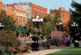 Red-brick buildings stand behind trees and flowerbeds in Downtown Pueblo