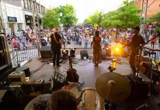 A band plays at Greeley's Friday Fest on a stage in front of a crowd gathered along a downtown street