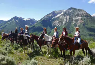 A group of people on horseback posed in front of a mountain range in Marble, Colorado