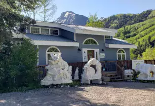 Several intricately carved statues made of white marble sit outside a grey building