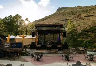 Musicians on an outdoor stage with cliffs in the background at tThe Mishawaka Summer Concert Series in Fort Collins, Colorado