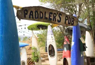 Multi-colored kayaks and white bistro lights hang as decoration next to a sign bearing the name of Paddler's Pub in Fort Collins, Colorado