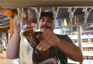 A bartender fills a growler full of beer behind the bar at New Belgium Brewing.
