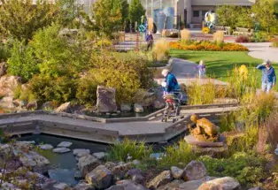 Adults and a child explore the paths in Gardens on Spring Creek in Fort Collins. The gardens feature plants, sculptures and water features.