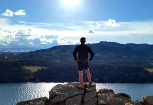 A hiker stand atop a rocky cliff overlooking Horsetooth Reservoir near Fort Collins, Colorado.