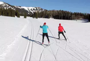 Two people skate-skiing on a groomed Nordic ski track near Montrose