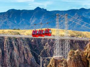See the gorge from every angle with the Aerial Gondola. Red gondolas over a vast canyon with a mountain backdrop.